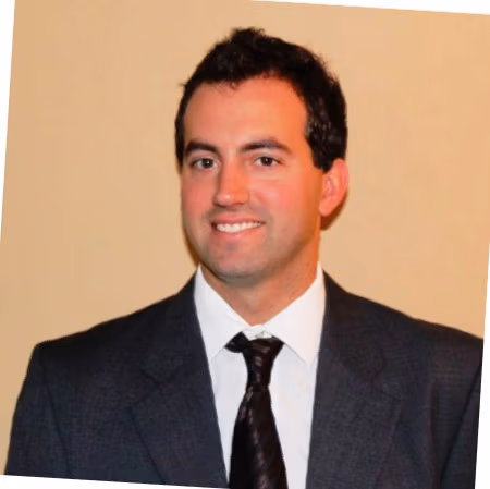 Portrait of a man in a dark suit and tie, smiling at the camera.